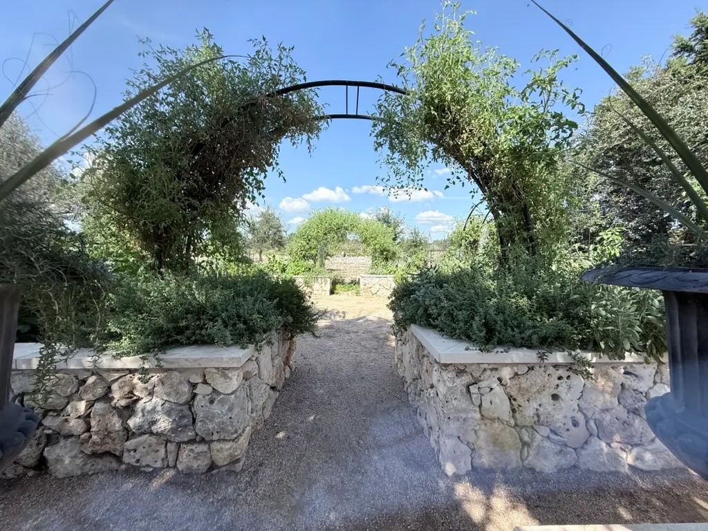 Garden archway with metal frame between stone walls along gravel pathway in Spring Branch